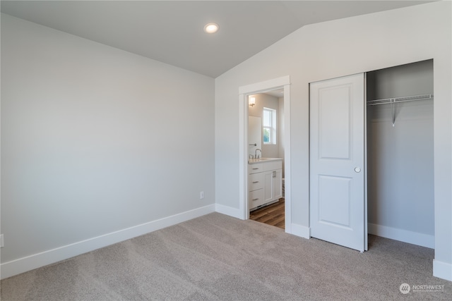 unfurnished bedroom with a closet, carpet, lofted ceiling, and sink