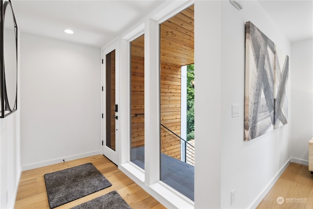 doorway to outside with wood walls and light hardwood / wood-style flooring