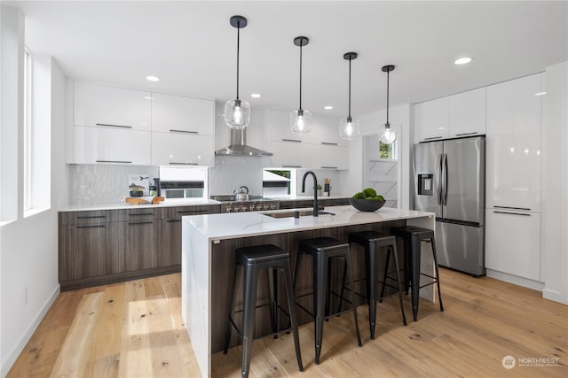 kitchen with light hardwood / wood-style floors, white cabinetry, a kitchen island with sink, and stainless steel fridge with ice dispenser