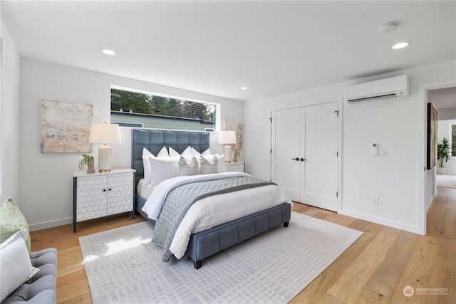 bedroom with light hardwood / wood-style floors and a wall unit AC