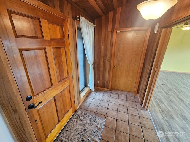 interior space with wood walls, ceiling fan, light hardwood / wood-style floors, and wooden ceiling