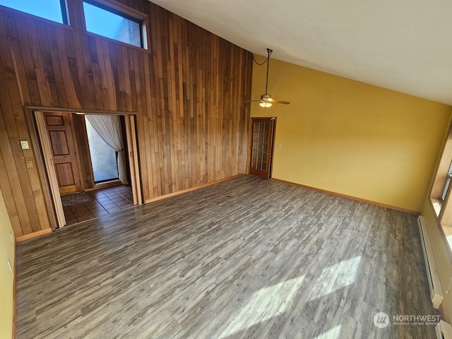 additional living space featuring high vaulted ceiling, plenty of natural light, dark wood-type flooring, and wood walls