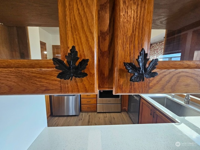 kitchen with sink, built in desk, stainless steel appliances, and light wood-type flooring