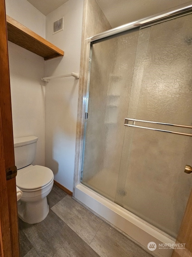 bathroom with a shower with shower door and toilet