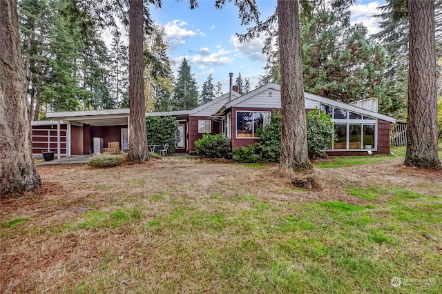 exterior space featuring a front lawn, a sunroom, and a carport