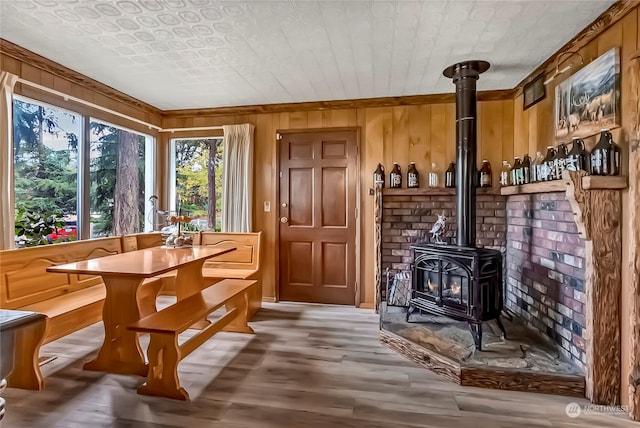 interior space with a wood stove, ornamental molding, wooden walls, and hardwood / wood-style floors