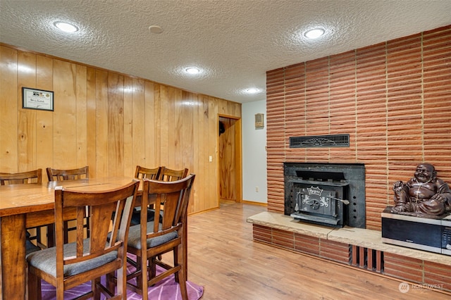 dining area featuring a textured ceiling, light hardwood / wood-style flooring, and wooden walls