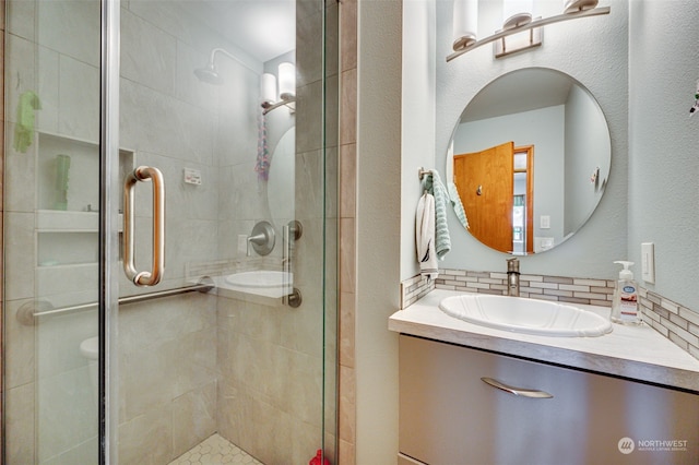 bathroom featuring vanity, tasteful backsplash, and a shower with shower door