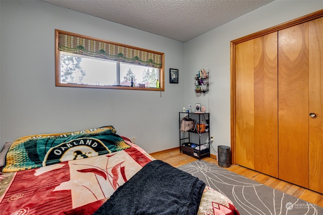 bedroom with a closet, light hardwood / wood-style floors, and a textured ceiling