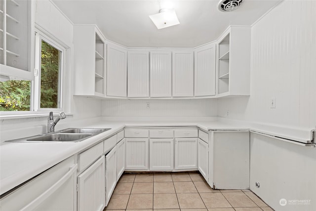 kitchen with light tile patterned floors, white dishwasher, sink, and white cabinets