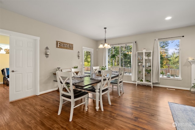 dining room featuring a notable chandelier, a healthy amount of sunlight, and dark hardwood / wood-style flooring