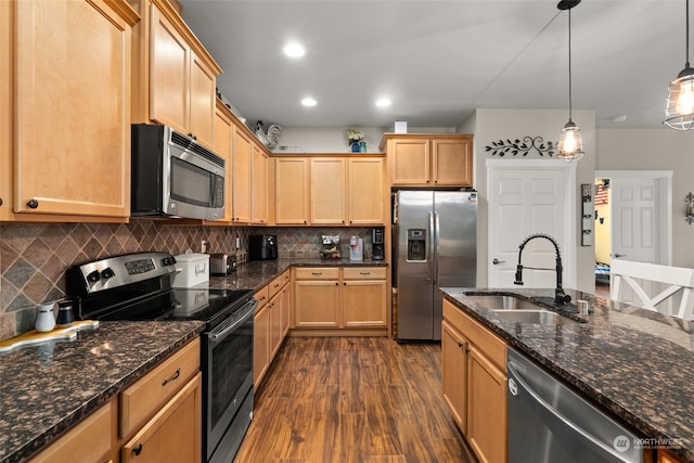 kitchen with appliances with stainless steel finishes, dark stone counters, dark hardwood / wood-style floors, sink, and decorative light fixtures