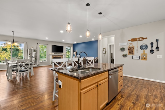 kitchen featuring sink, an island with sink, stainless steel dishwasher, dark stone countertops, and dark wood-type flooring