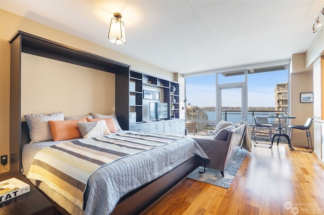 bedroom featuring expansive windows and light hardwood / wood-style flooring