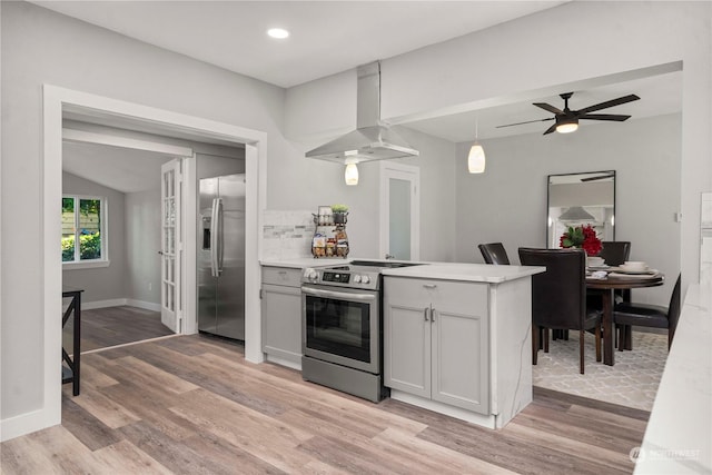 1106 Starling St, Steilacoom, WA 98388 - kitchen with appliances with stainless steel finishes, wall chimney range hood, light wood-style floors, a peninsula, and vaulted ceiling