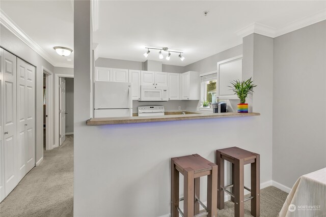 kitchen with white appliances, crown molding, white cabinetry, and light colored carpet