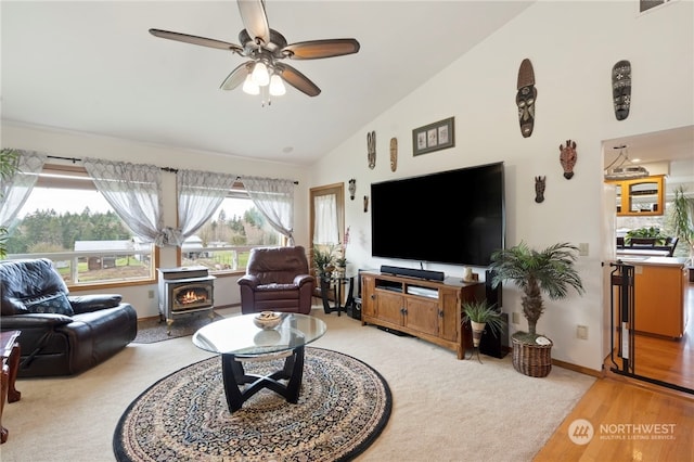 living room featuring a wood stove, hardwood / wood-style floors, high vaulted ceiling, and ceiling fan