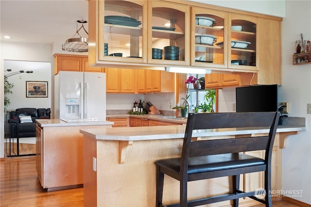 kitchen with white fridge with ice dispenser, kitchen peninsula, light wood-type flooring, and a breakfast bar