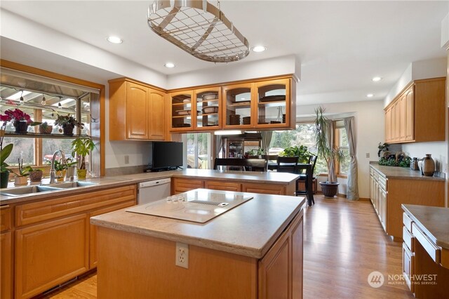 kitchen featuring dishwasher, kitchen peninsula, sink, a center island, and light wood-type flooring