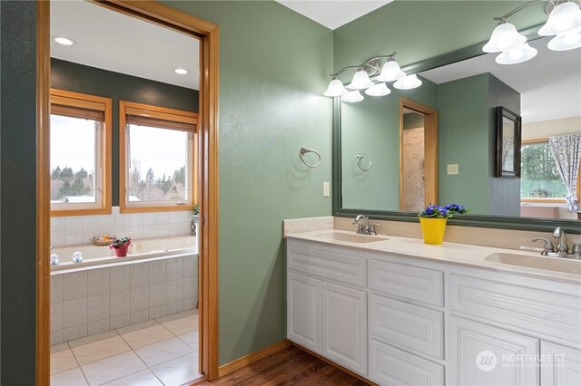 bathroom with a wealth of natural light, vanity, tiled tub, and tile patterned flooring