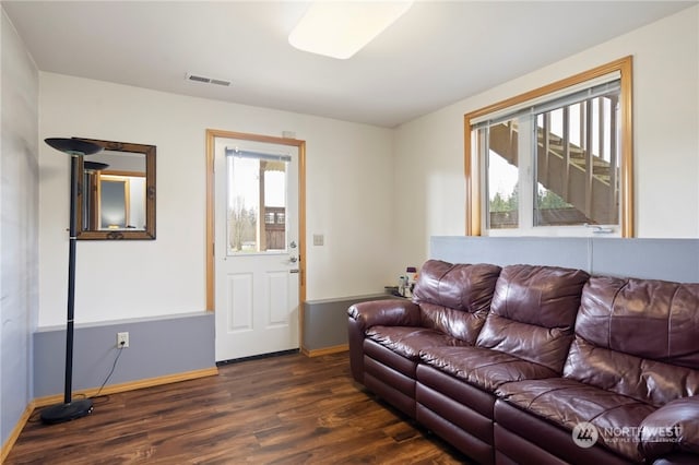 living room with dark wood-type flooring and a healthy amount of sunlight