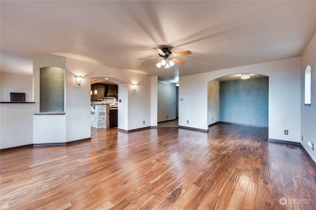 212 Grandview Ave, Camano Island, WA 98282 - unfurnished living room with arched walkways, baseboards, a ceiling fan, and wood finished floors