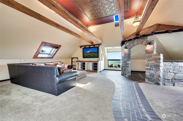 carpeted living room featuring lofted ceiling with skylight and ornate columns