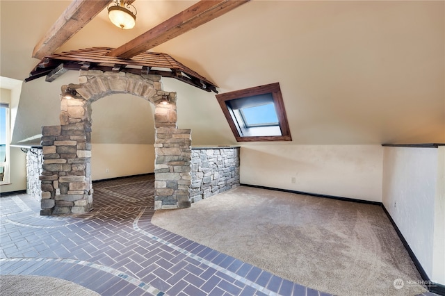 interior space featuring lofted ceiling with skylight, ornate columns, and carpet floors