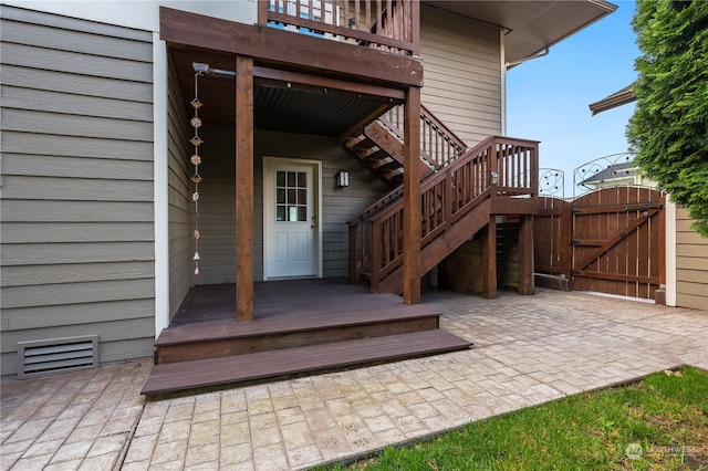 entrance to property featuring a patio and a wooden deck