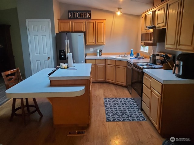 kitchen featuring lofted ceiling, sink, light brown cabinetry, appliances with stainless steel finishes, and light hardwood / wood-style floors