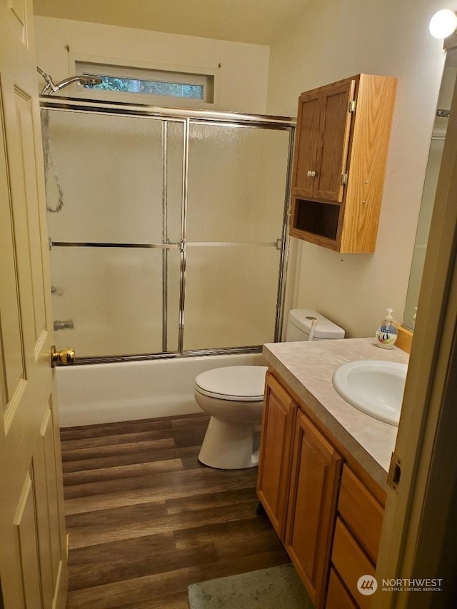 full bathroom featuring vanity, bath / shower combo with glass door, wood-type flooring, and toilet