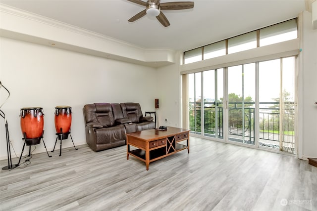 living room featuring ceiling fan, ornamental molding, and light wood-type flooring