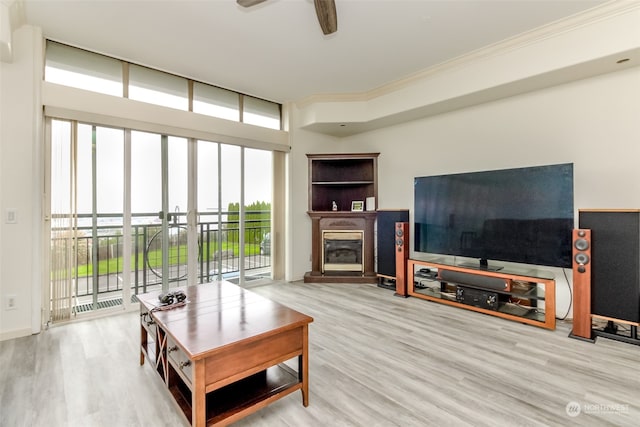 living room with ornamental molding, light wood-type flooring, and ceiling fan