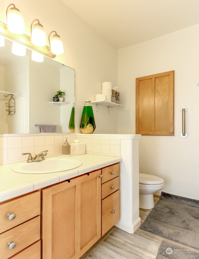 bathroom with vanity, decorative backsplash, hardwood / wood-style flooring, and toilet