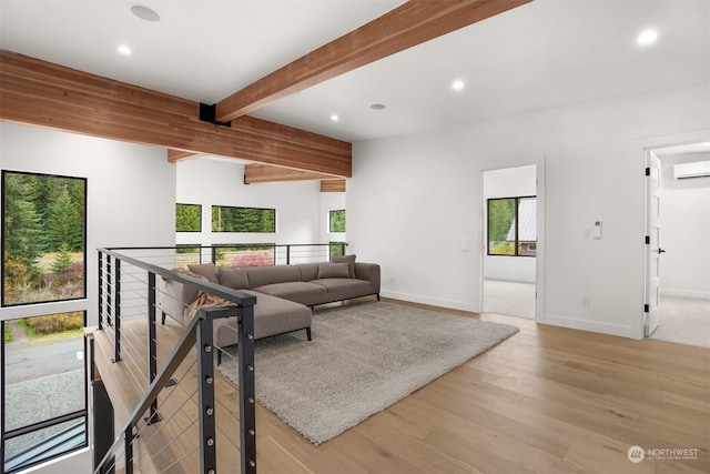 living room with light hardwood / wood-style floors, a wall mounted AC, and beam ceiling