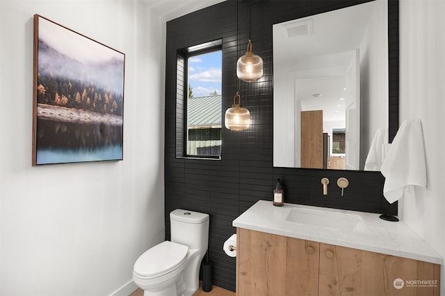 bathroom featuring vanity, toilet, and tile walls