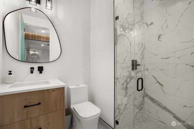 bathroom with a shower with door, vanity, and toilet