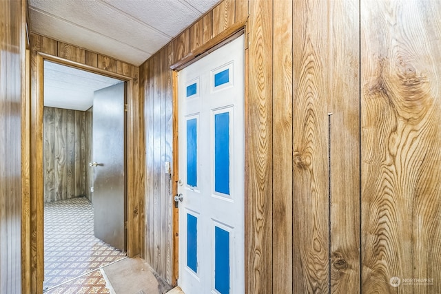 corridor featuring wooden walls and a textured ceiling