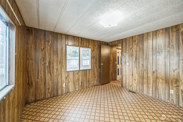 unfurnished room with a textured ceiling and wood walls