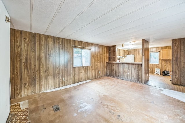 unfurnished room featuring plenty of natural light, concrete floors, and wooden walls