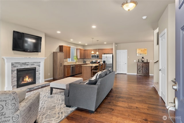 living room featuring a stone fireplace and dark hardwood / wood-style floors