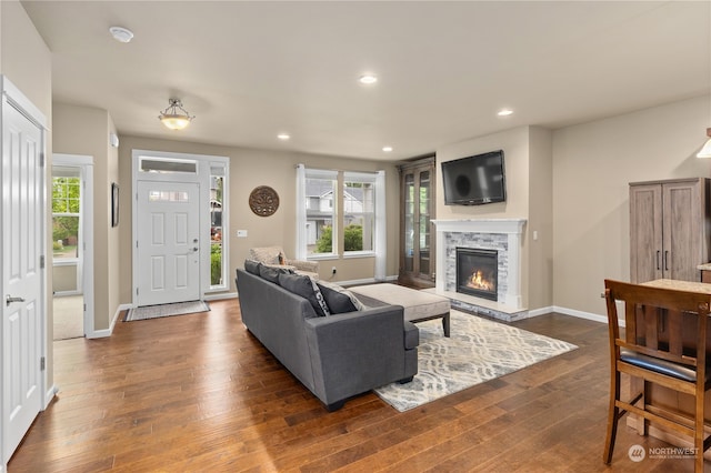 living room featuring dark wood-type flooring, a wealth of natural light, and a fireplace