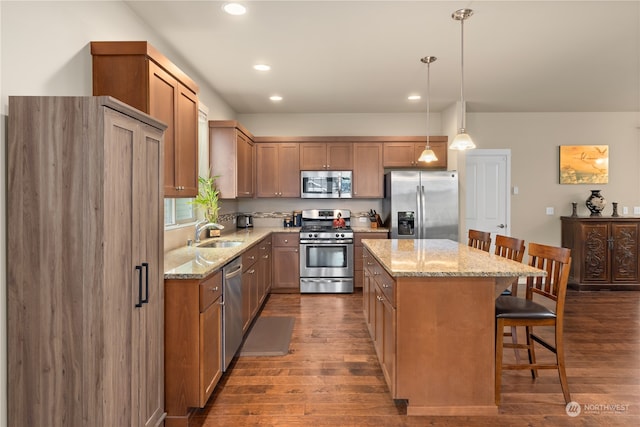 kitchen with sink, a center island, stainless steel appliances, decorative light fixtures, and dark wood-type flooring