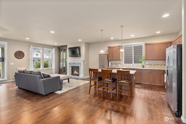 kitchen featuring a kitchen island, pendant lighting, dark wood-type flooring, a breakfast bar, and stainless steel refrigerator with ice dispenser