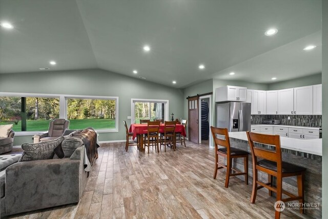 interior space with light hardwood / wood-style floors, lofted ceiling, and a barn door