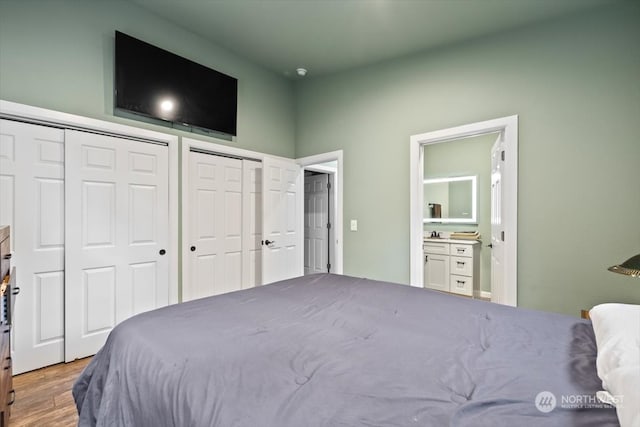 bedroom featuring multiple closets, hardwood / wood-style floors, and ensuite bathroom