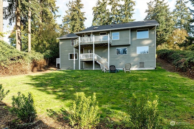 back of house featuring a balcony and a yard