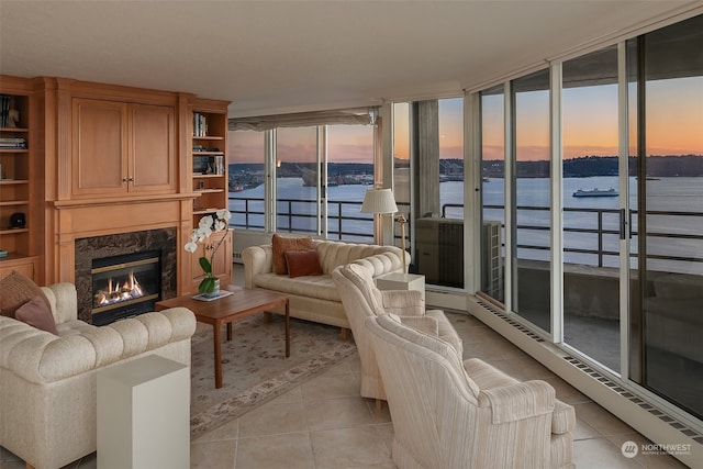 living room with a high end fireplace, a water view, and light tile patterned flooring