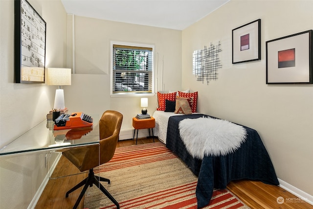 bedroom with a baseboard heating unit and hardwood / wood-style flooring