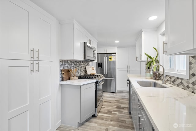 kitchen featuring light hardwood / wood-style floors, white cabinets, stainless steel appliances, and light stone counters